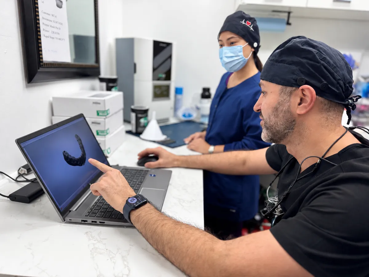 Dr. Amin Ehsan reviewing a digital implant plan on a laptop